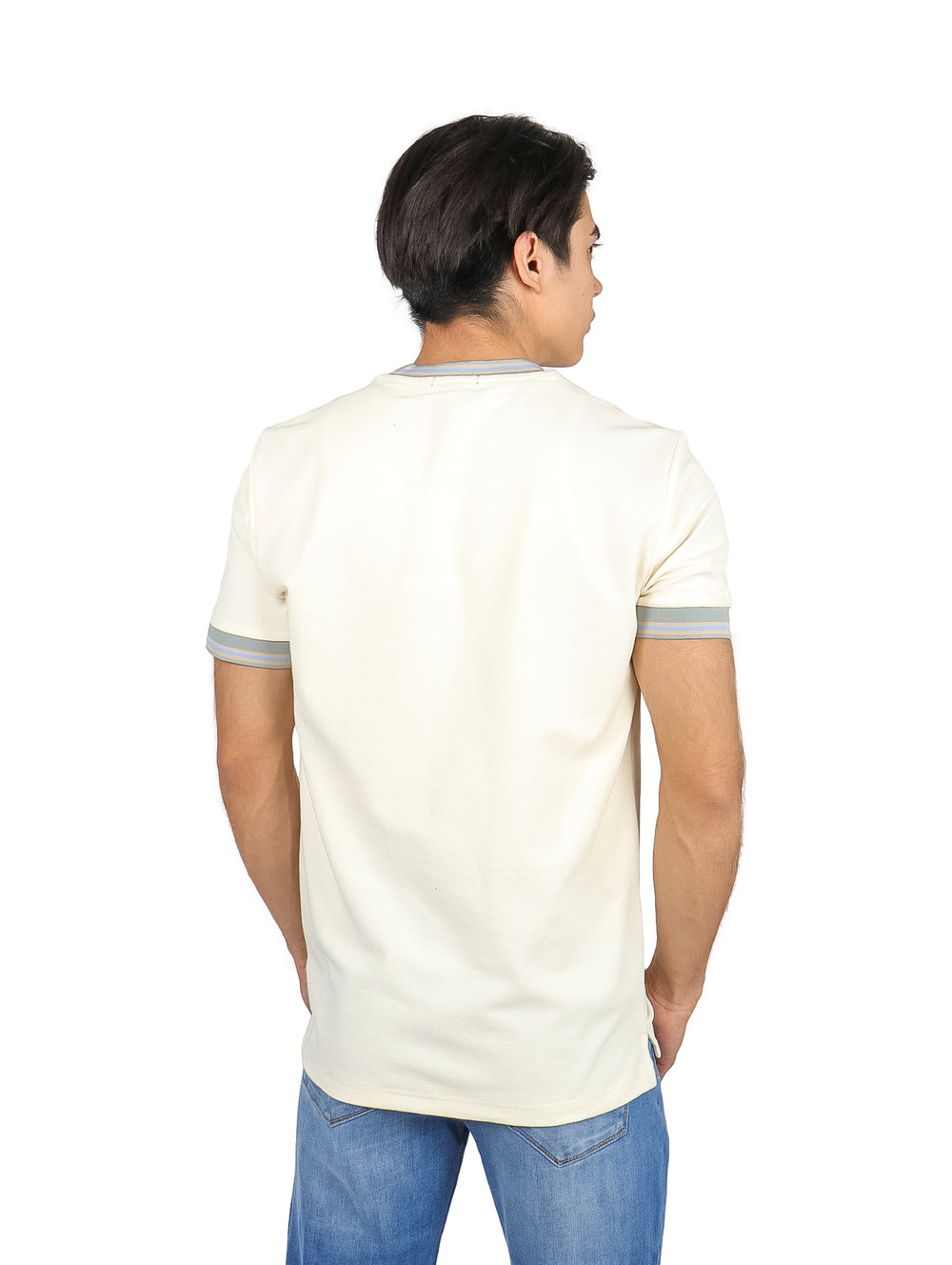 Hombre vistiendo playera color off white con ribetes grises en el cuello y los bordes de las mangas.