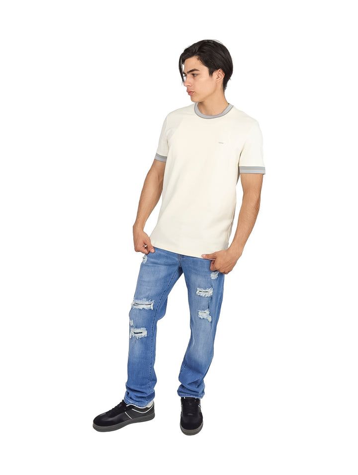 Hombre vistiendo playera color off white con ribetes grises en el cuello y los bordes de las mangas.