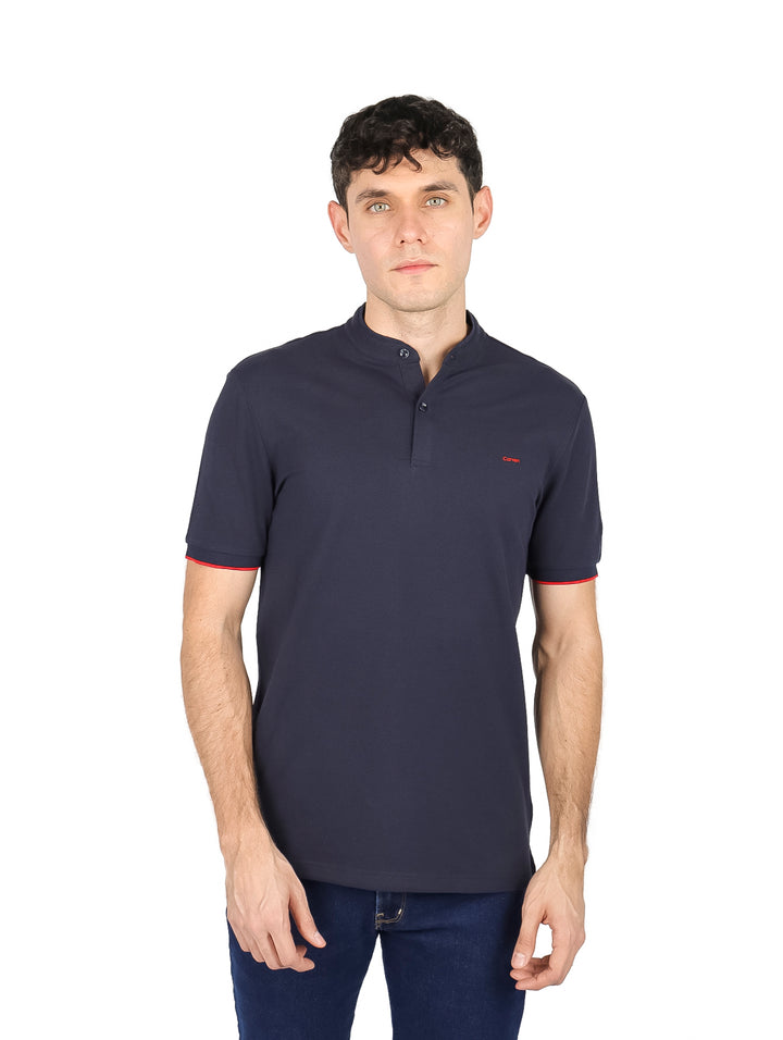 Hombre vistiendo playera azul marino de manga corta con cuello mao y detalle rojo en las mangas.
