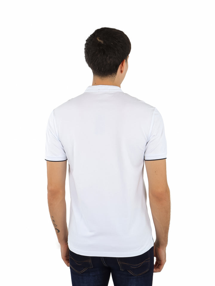 Hombre vistiendo playera blanca de manga corta con cuello mao y detalles negros en los bordes de las mangas.