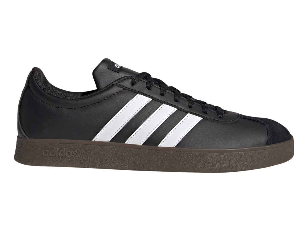 Tenis Adidas color negro con tres franjas blancas laterales y suela marrón oscuro.