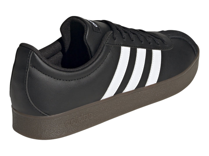 Tenis Adidas color negro con tres franjas blancas laterales y suela marrón oscuro.