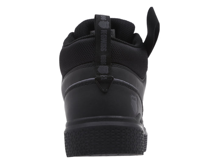 Tenis K-Swiss color negro, estilo mid-top con correa ajustable en el tobillo y suela texturizada.