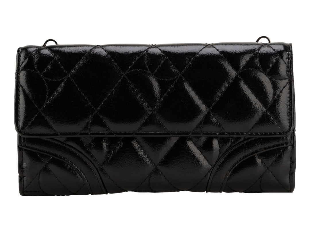 Bolso negro brillante de la marca Cloe con diseño acolchado y correa para el hombro.