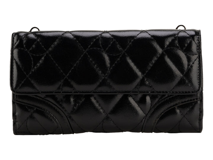 Bolso negro brillante de la marca Cloe con diseño acolchado y correa para el hombro.