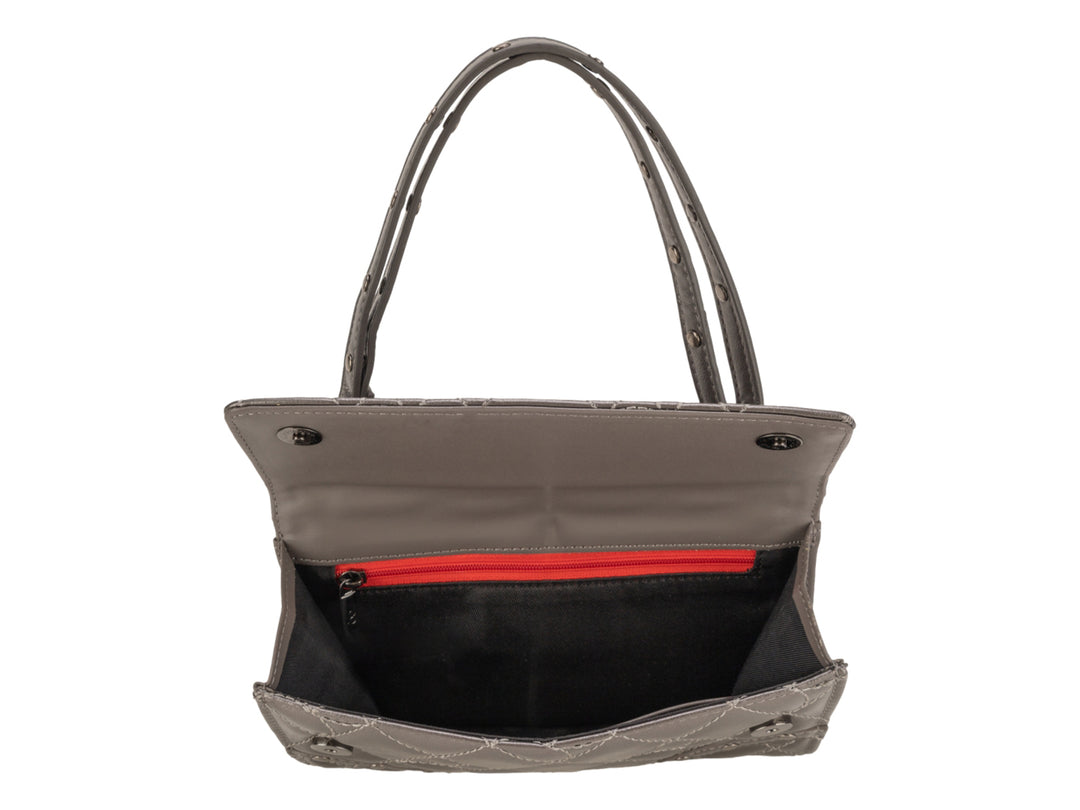 Bolso de mano Cloe color plata con acabado brillante, diseño acolchado y asa larga.