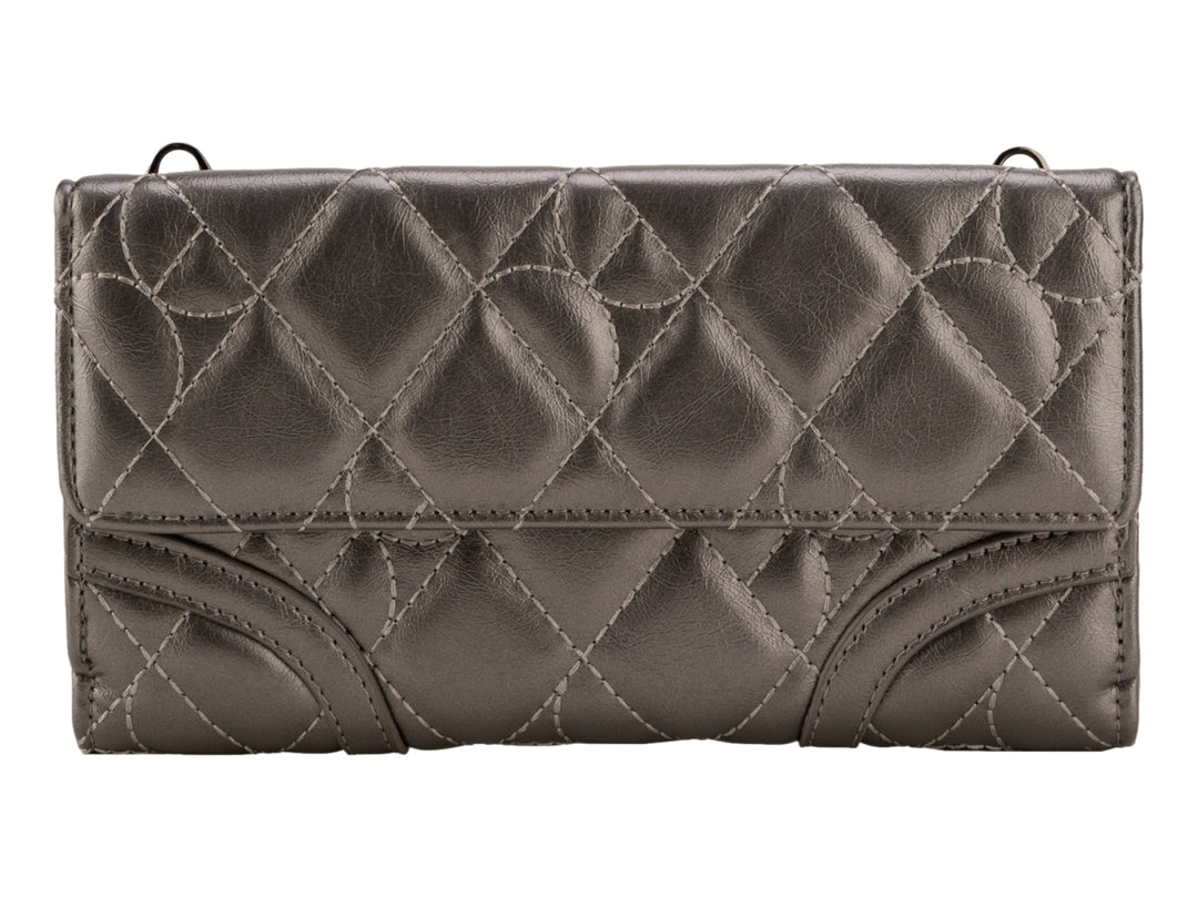 Bolso de mano Cloe color plata con acabado brillante, diseño acolchado y asa larga.