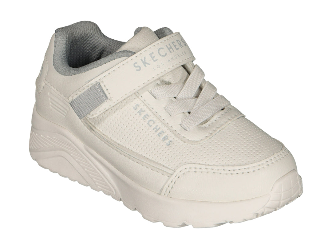 Tenis blancos Skechers con cierre de velcro y agujetas sobre fondo blanco.