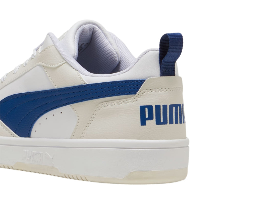 Tenis PUMA Rebound V6 Low en color blanco con detalles en azul y gris, diseño deportivo de corte bajo.