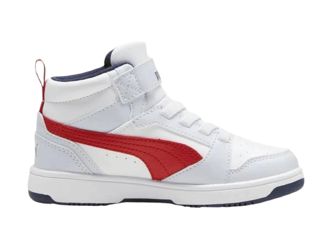 Tenis PUMA blancos de corte medio con franja roja lateral y suela azul marino.