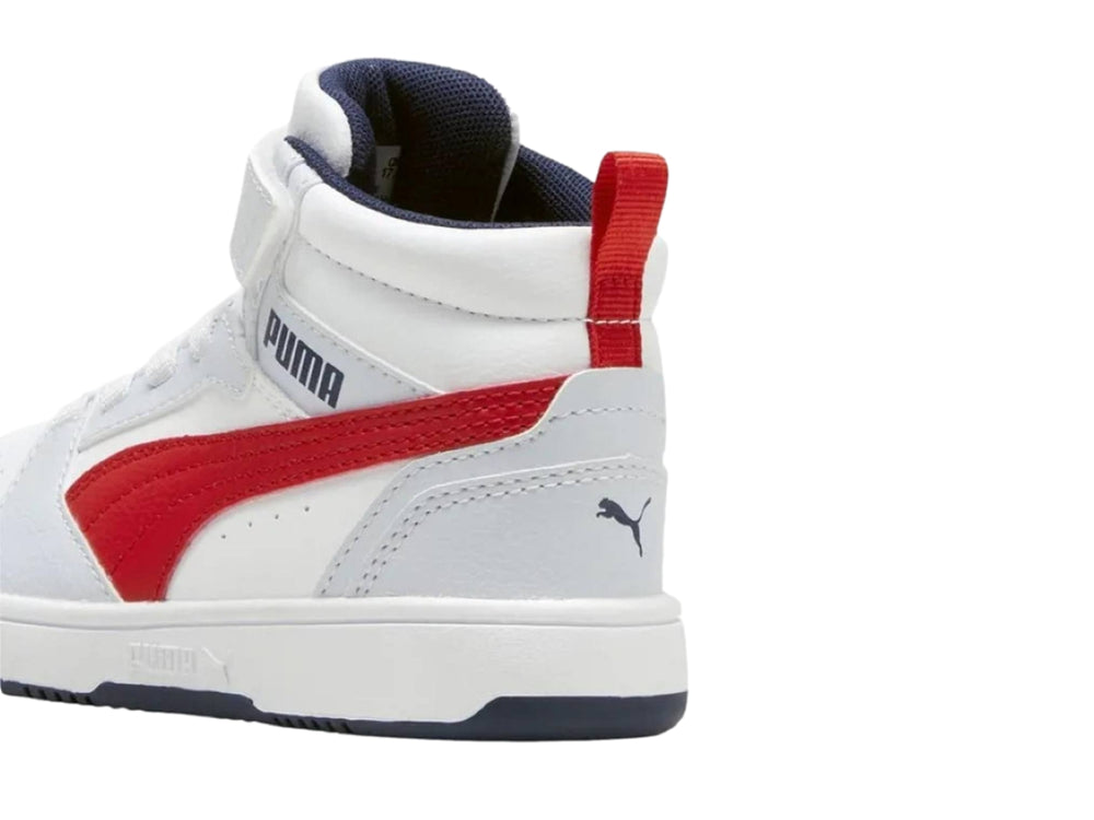 Tenis PUMA blancos de corte medio con franja roja lateral y suela azul marino.