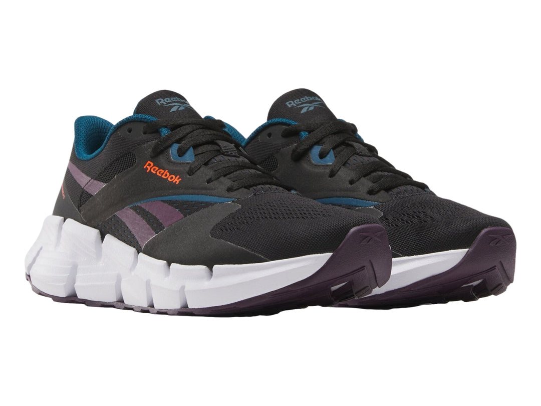 Tenis deportivos Reebok Zig Dynamica color negro con suela blanca y detalles en morado.