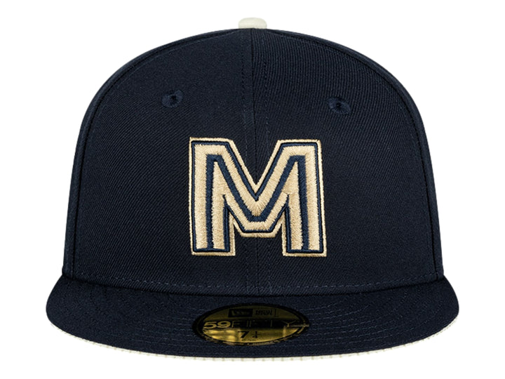 Gorra New Era color navy con letra M bordada en dorado y visera plana.