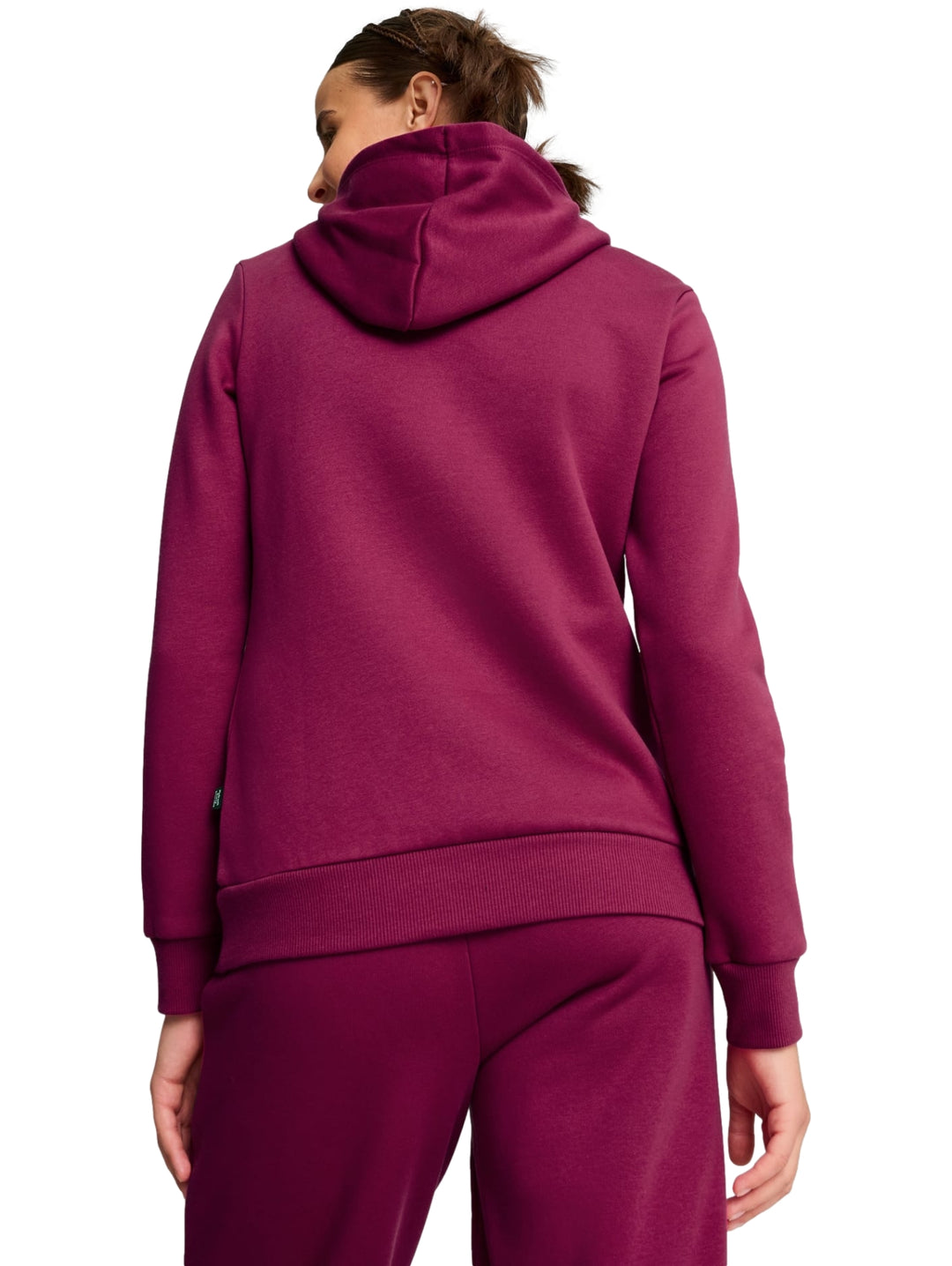Mujer vistiendo sudadera con capucha y pantalones deportivos color magenta con logotipo de PUMA en blanco.