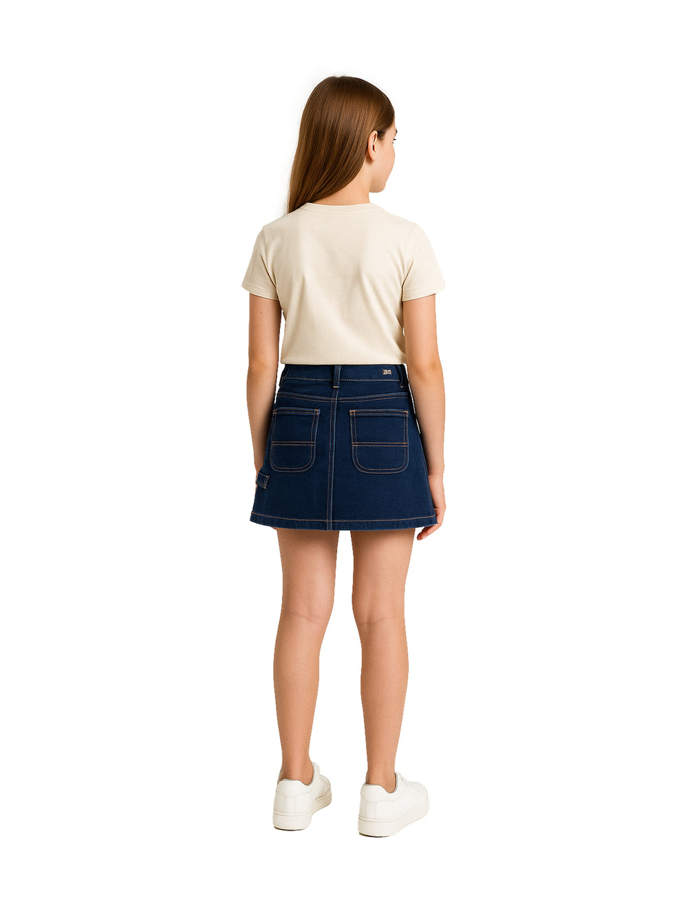 Niña vistiendo una falda corta de mezclilla azul oscuro estilo cargo con camiseta beige y tenis blancos.