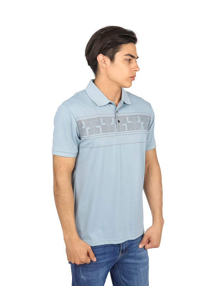 Hombre vistiendo playera polo color azul claro con detalle geométrico en el pecho.