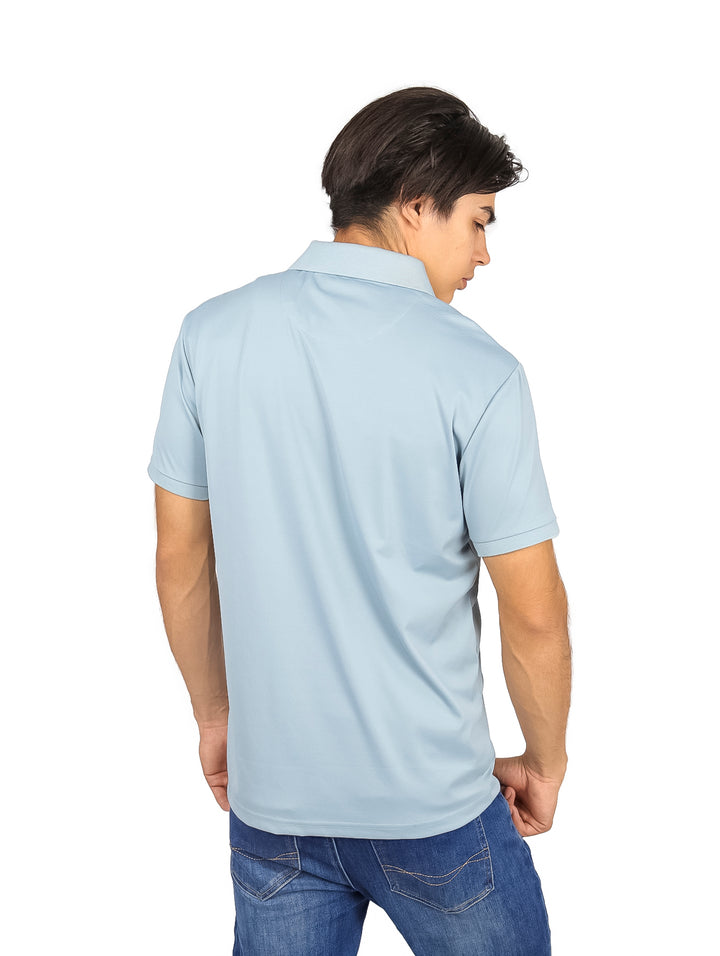 Hombre vistiendo playera polo color azul claro con detalle geométrico en el pecho.