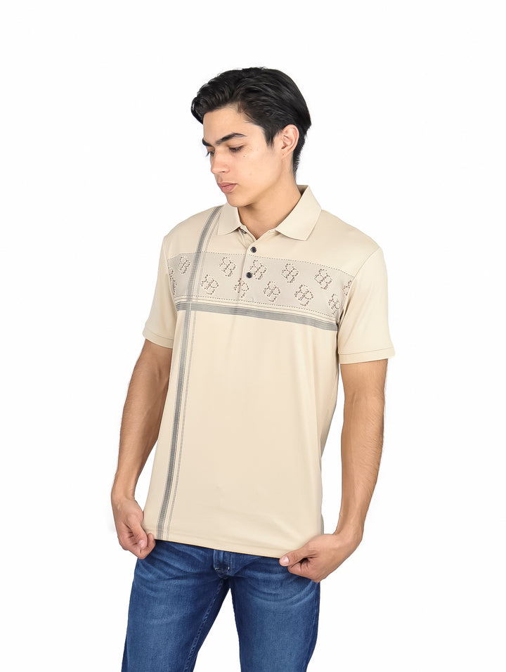 Hombre vistiendo una playera polo color beige con detalles decorativos en el pecho y un costado.