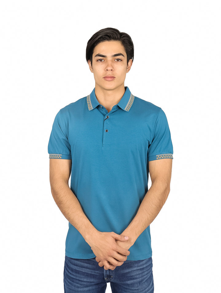 Hombre vistiendo una playera polo color teal con detalles decorativos en el cuello y las mangas.