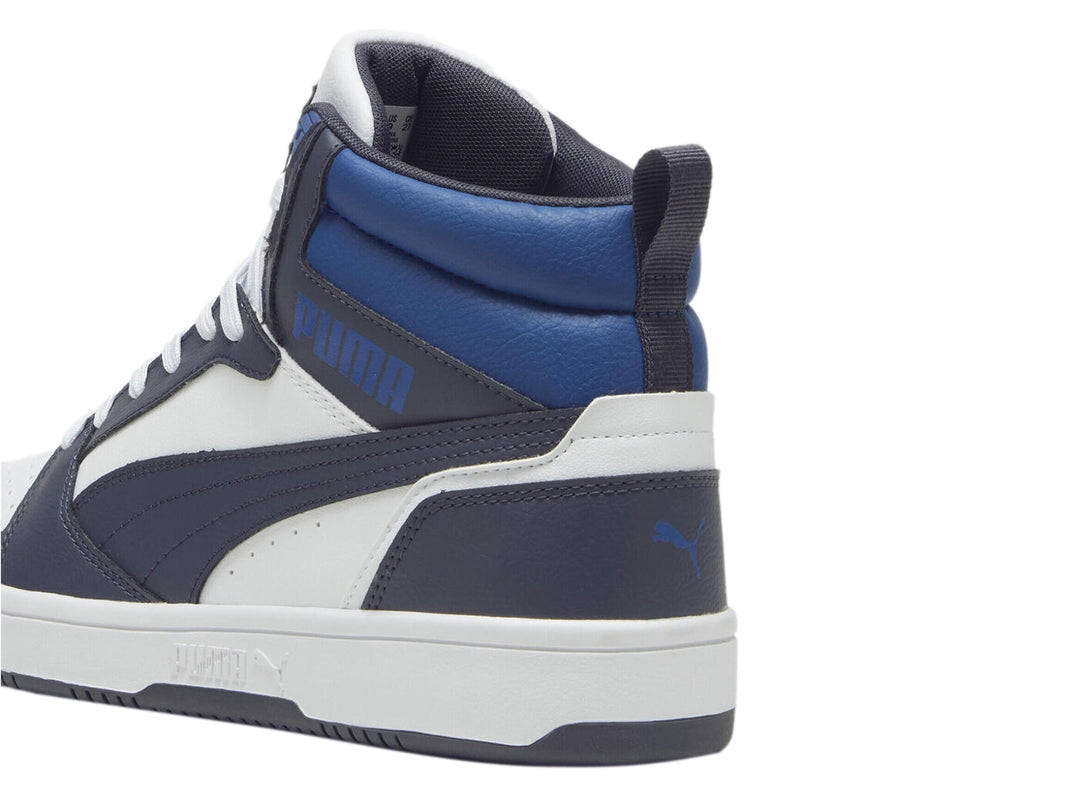 Tenis PUMA Rebound V6 de corte alto en colores blanco, gris y azul con suela blanca.