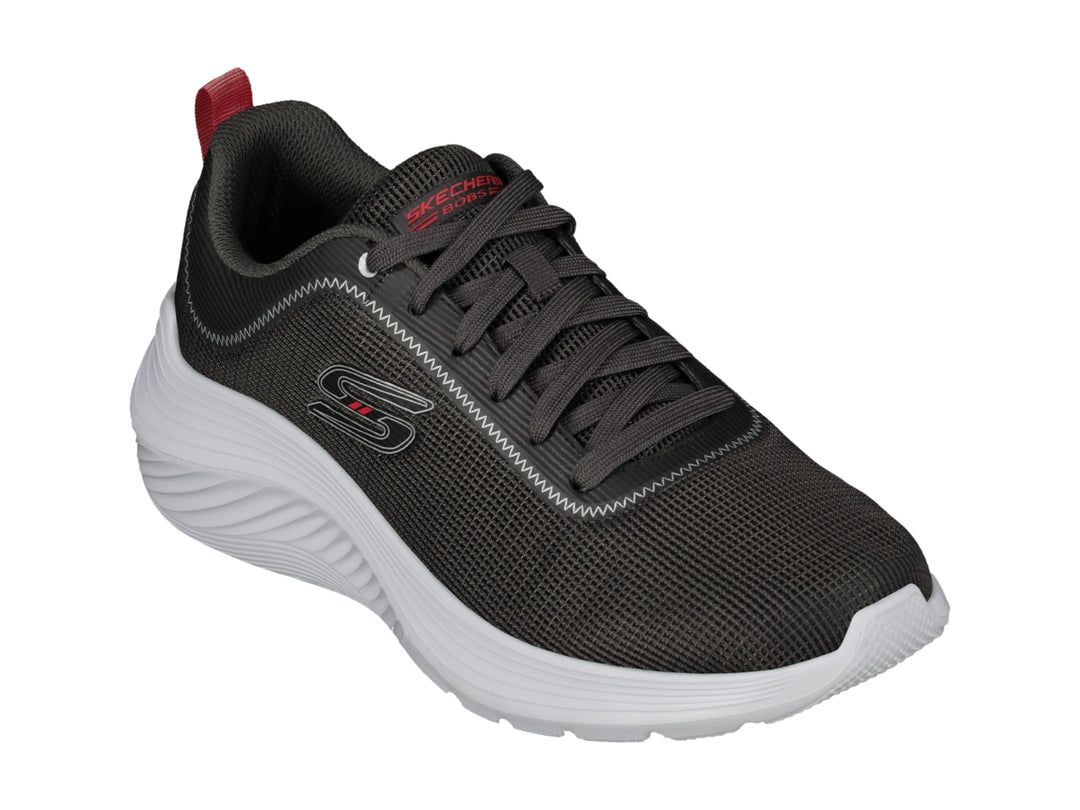 Tenis deportivos Skechers color gris con suela blanca y pequeña pestaña roja en el talón.