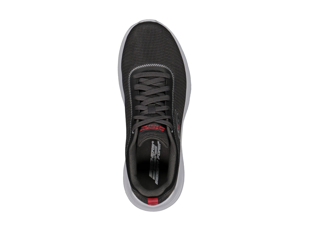 Tenis deportivos Skechers color gris con suela blanca y pequeña pestaña roja en el talón.