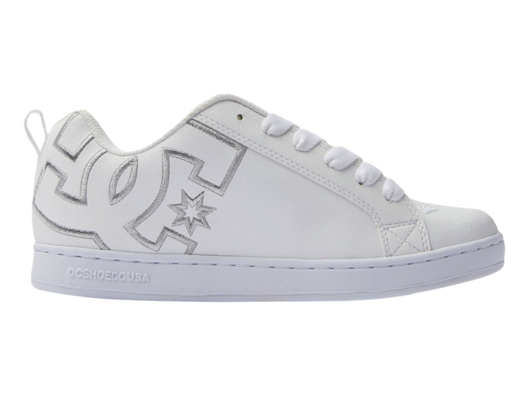 Tenis blancos DC Shoes con detalles gráficos plateados en el lateral y suela blanca.