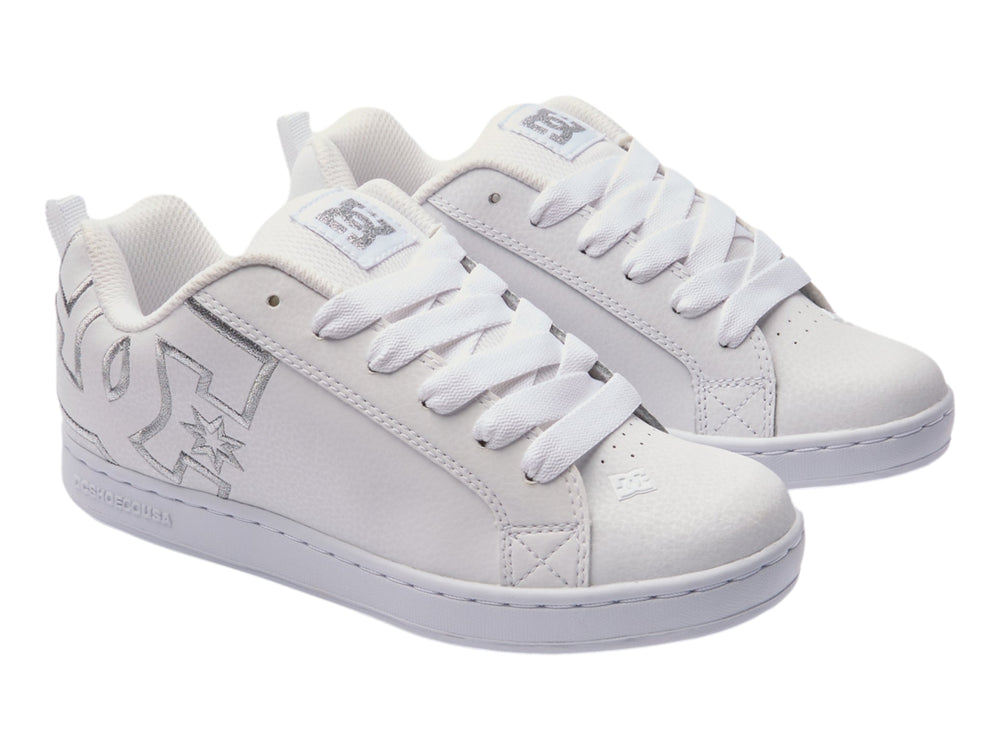 Tenis blancos DC Shoes con detalles gráficos plateados en el lateral y suela blanca.