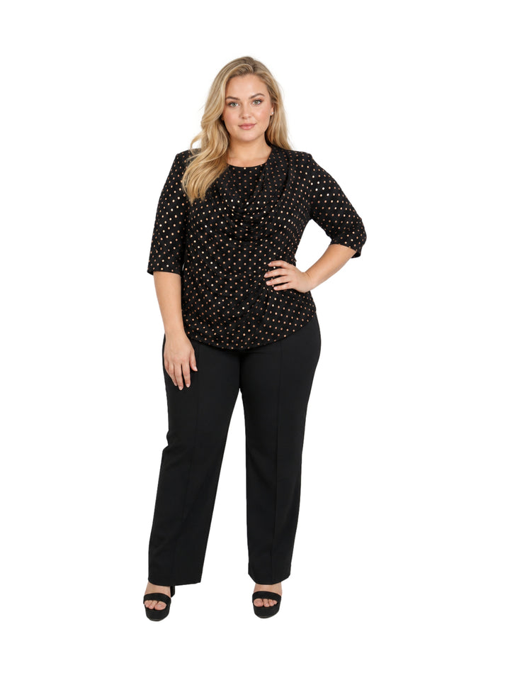 Mujer vistiendo blusa negra con lunares dorados y cuello drapeado.