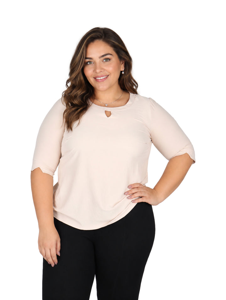 Mujer vistiendo blusa color hueso de manga tres cuartos y cuello redondo con detalle frontal.