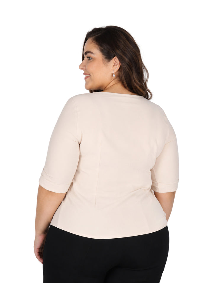 Mujer vistiendo blusa color hueso de manga tres cuartos y cuello redondo con detalle frontal.