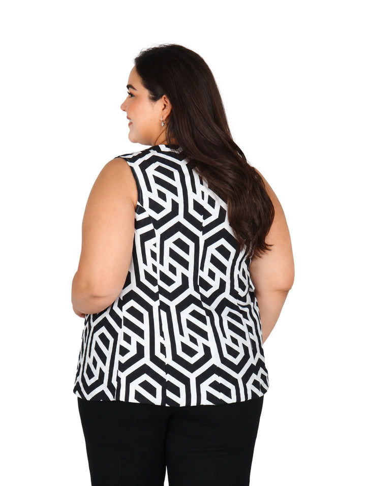 Mujer vistiendo un chaleco largo con estampado geométrico en colores negro y hueso sobre una blusa blanca.