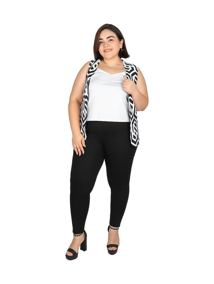 Mujer vistiendo un chaleco largo con estampado geométrico en colores negro y hueso sobre una blusa blanca.