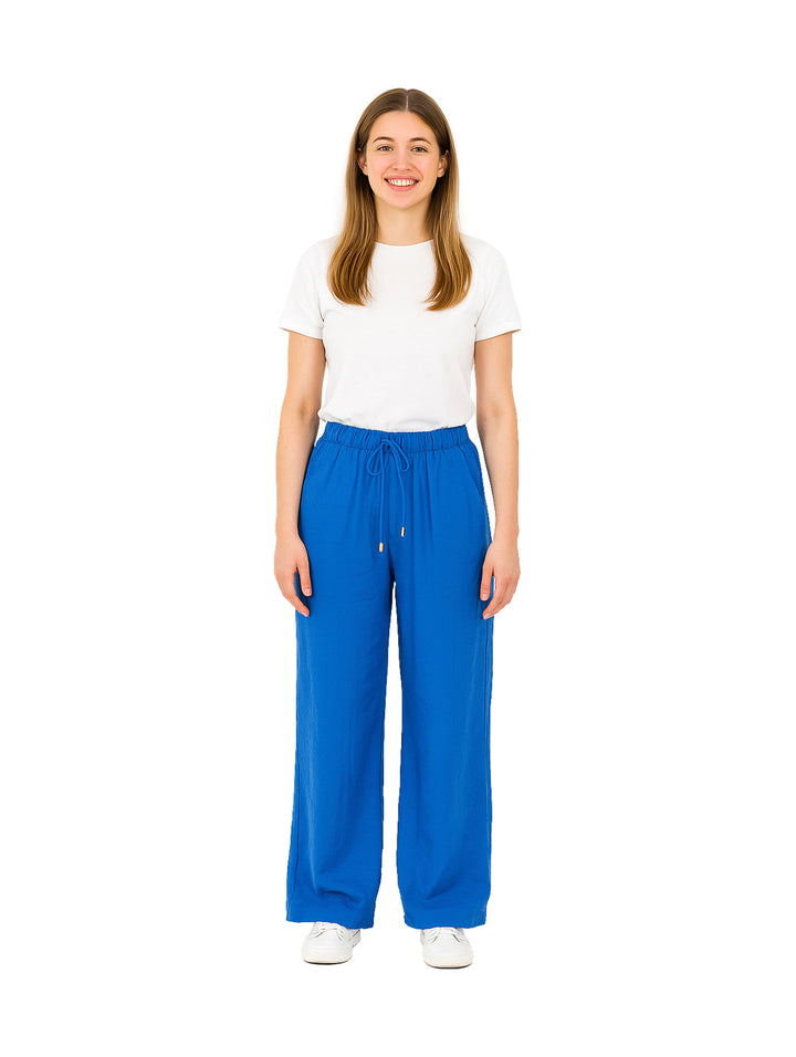 Mujer vistiendo pantalón de vestir azul rey de pierna ancha con cintura elástica y camiseta blanca.