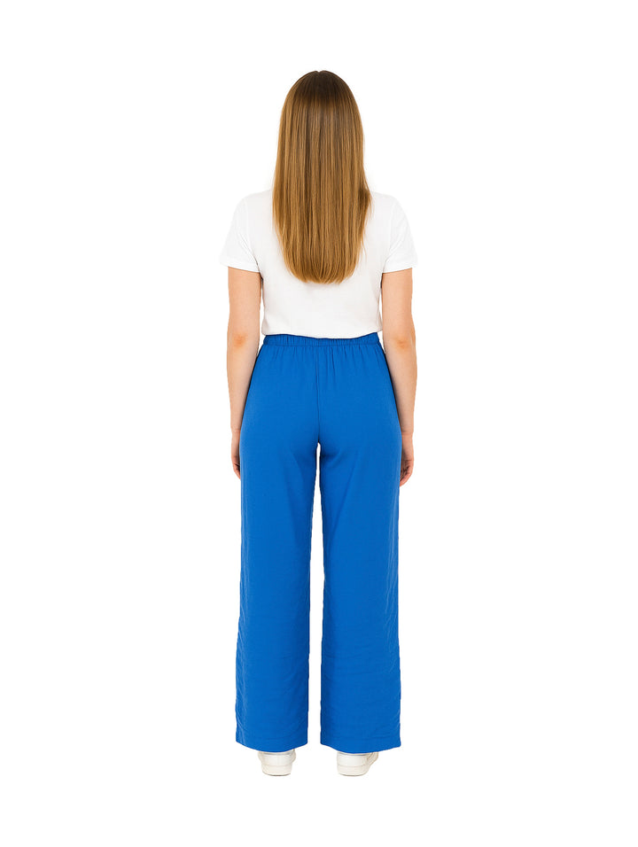 Mujer vistiendo pantalón de vestir azul rey de pierna ancha con cintura elástica y camiseta blanca.
