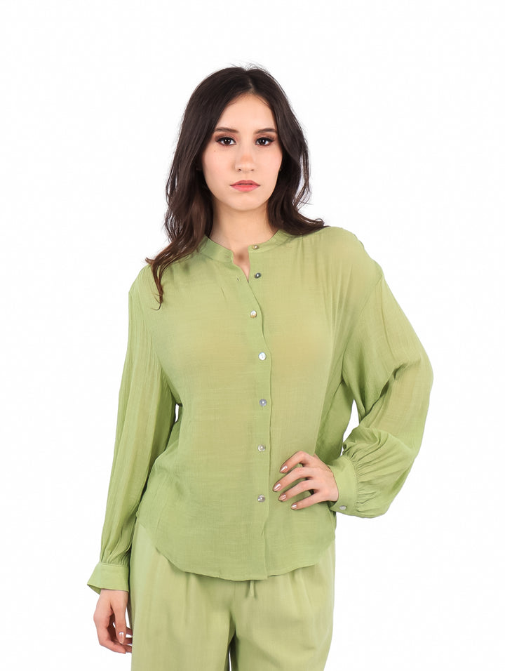 Mujer usando una camisa de botones color verde lima de manga larga.