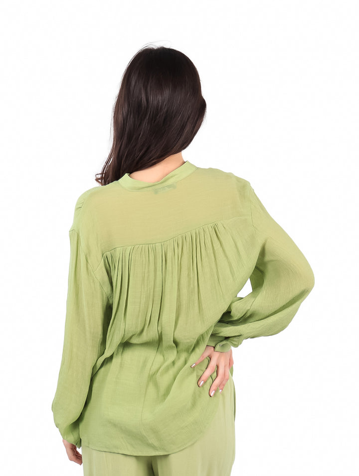 Mujer usando una camisa de botones color verde lima de manga larga.