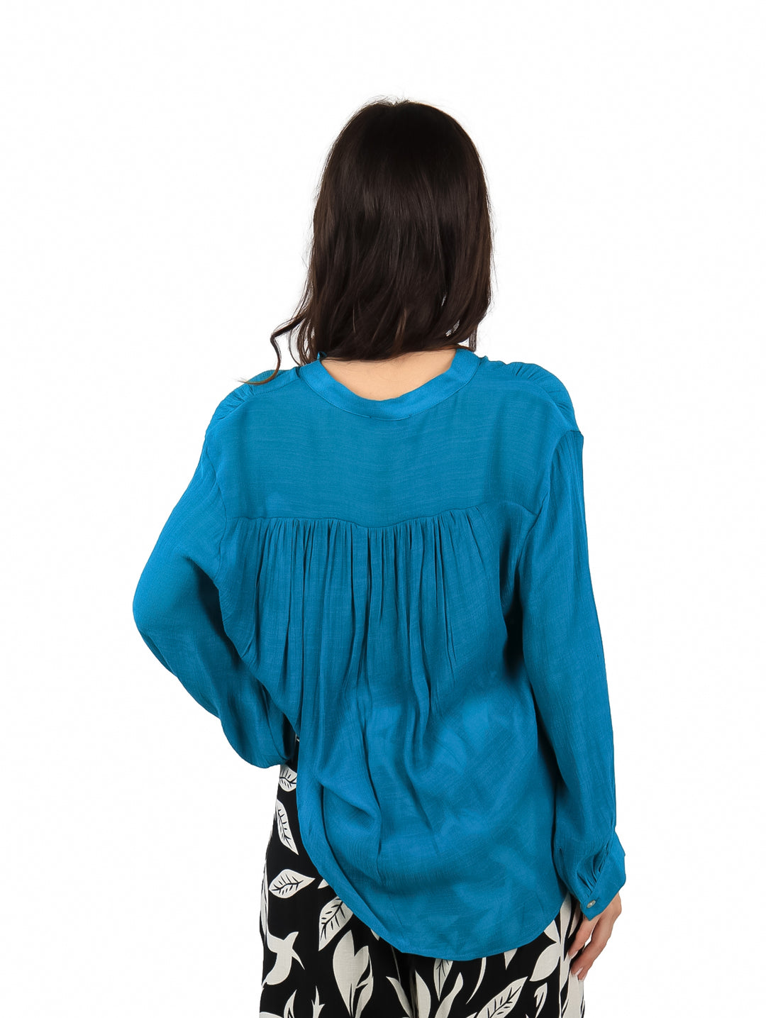 Mujer vistiendo una camisa azul de manga larga con botones frontales y corte holgado.