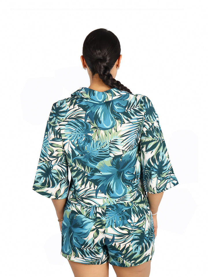 Mujer vistiendo blusa y shorts con estampado tropical en tonos verdes y azules.