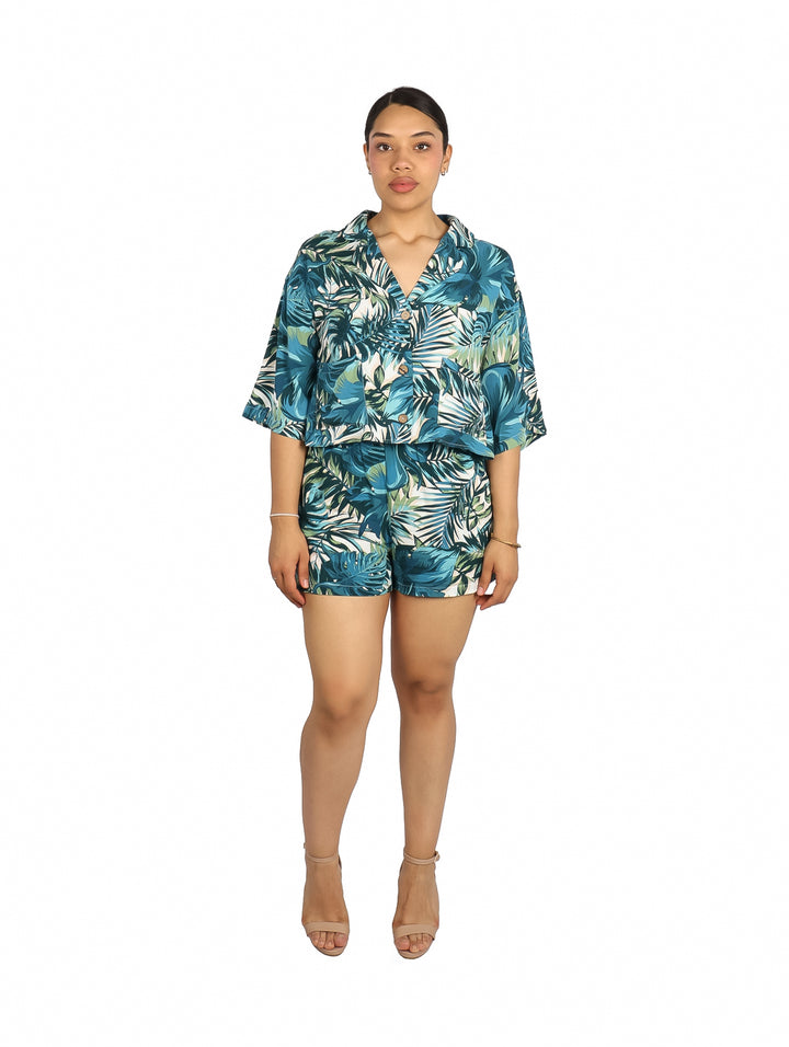 Mujer vistiendo blusa y shorts con estampado tropical en tonos verdes y azules.