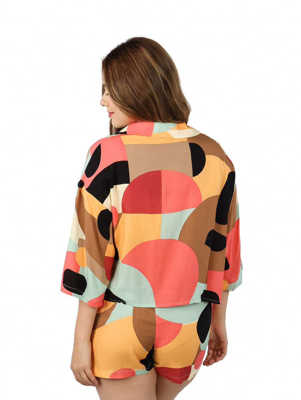 Mujer vistiendo blusa de manga corta con estampado geométrico multicolor.