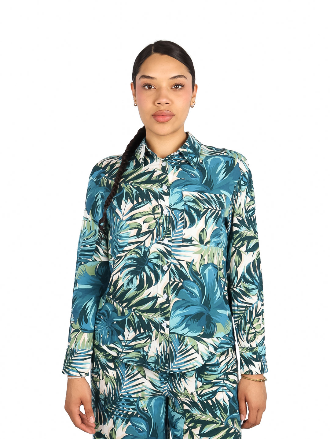 Mujer vistiendo camisa de manga larga con estampado de hojas tropicales en tonos verdes y azules.