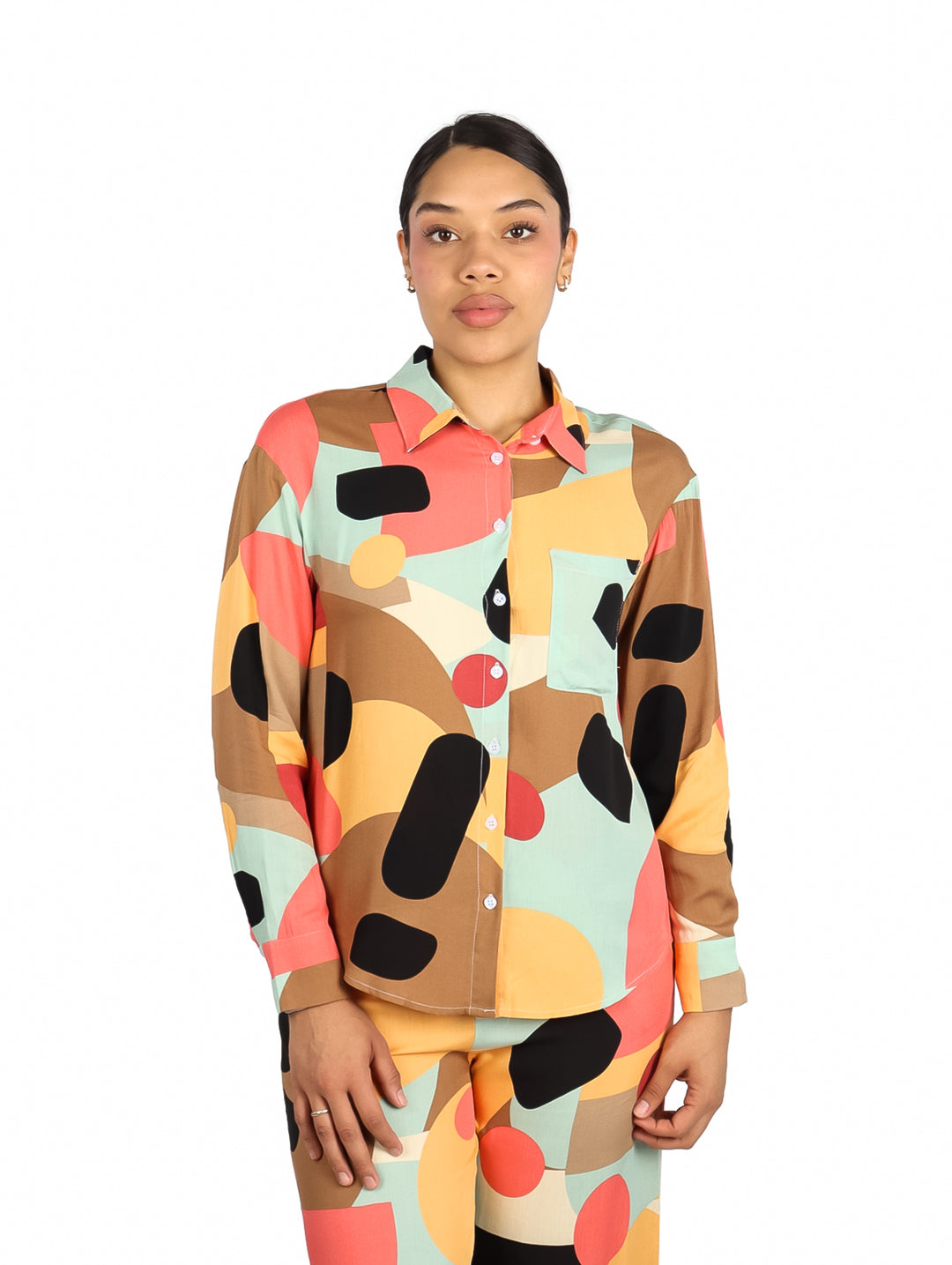 Mujer vistiendo camisa de manga larga con estampado geométrico multicolor en tonos marrón, verde menta y coral.