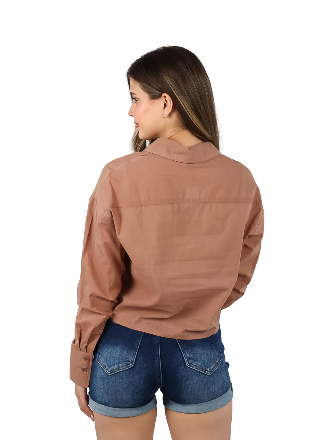 Mujer vistiendo una camisa marrón de botones manga larga y shorts de mezclilla.