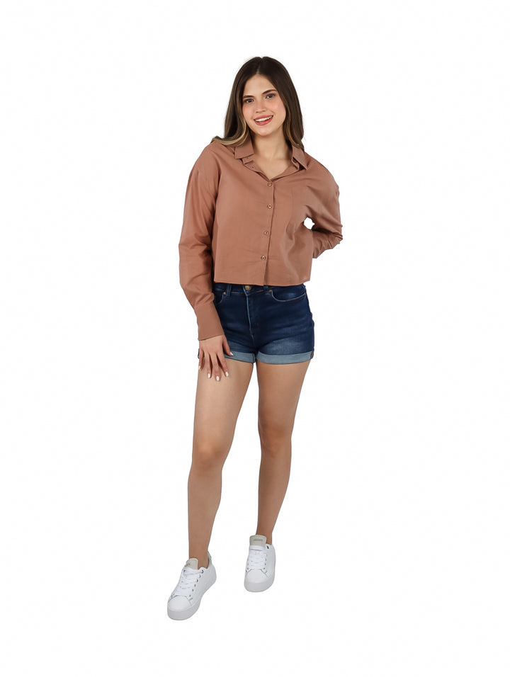Mujer vistiendo una camisa marrón de botones manga larga y shorts de mezclilla.