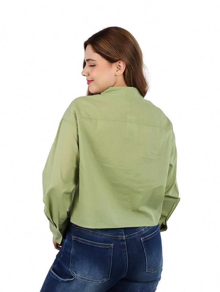 Mujer vistiendo una camisa verde de manga larga con botones y pantalones azules.