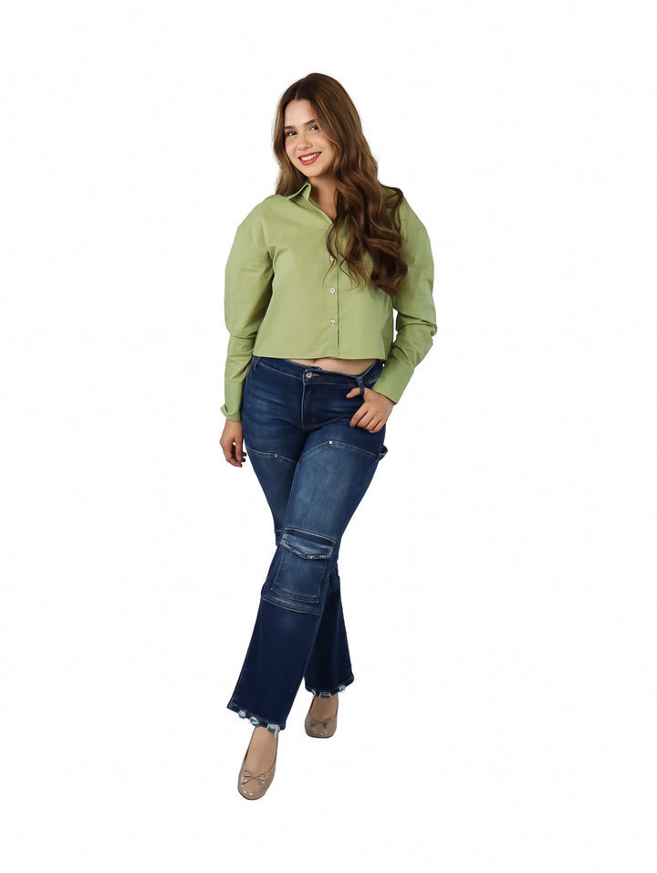 Mujer vistiendo una camisa verde de manga larga con botones y pantalones azules.