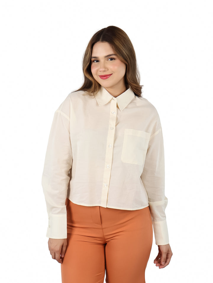 Mujer vistiendo una camisa color ivory de manga larga y pantalones naranja.