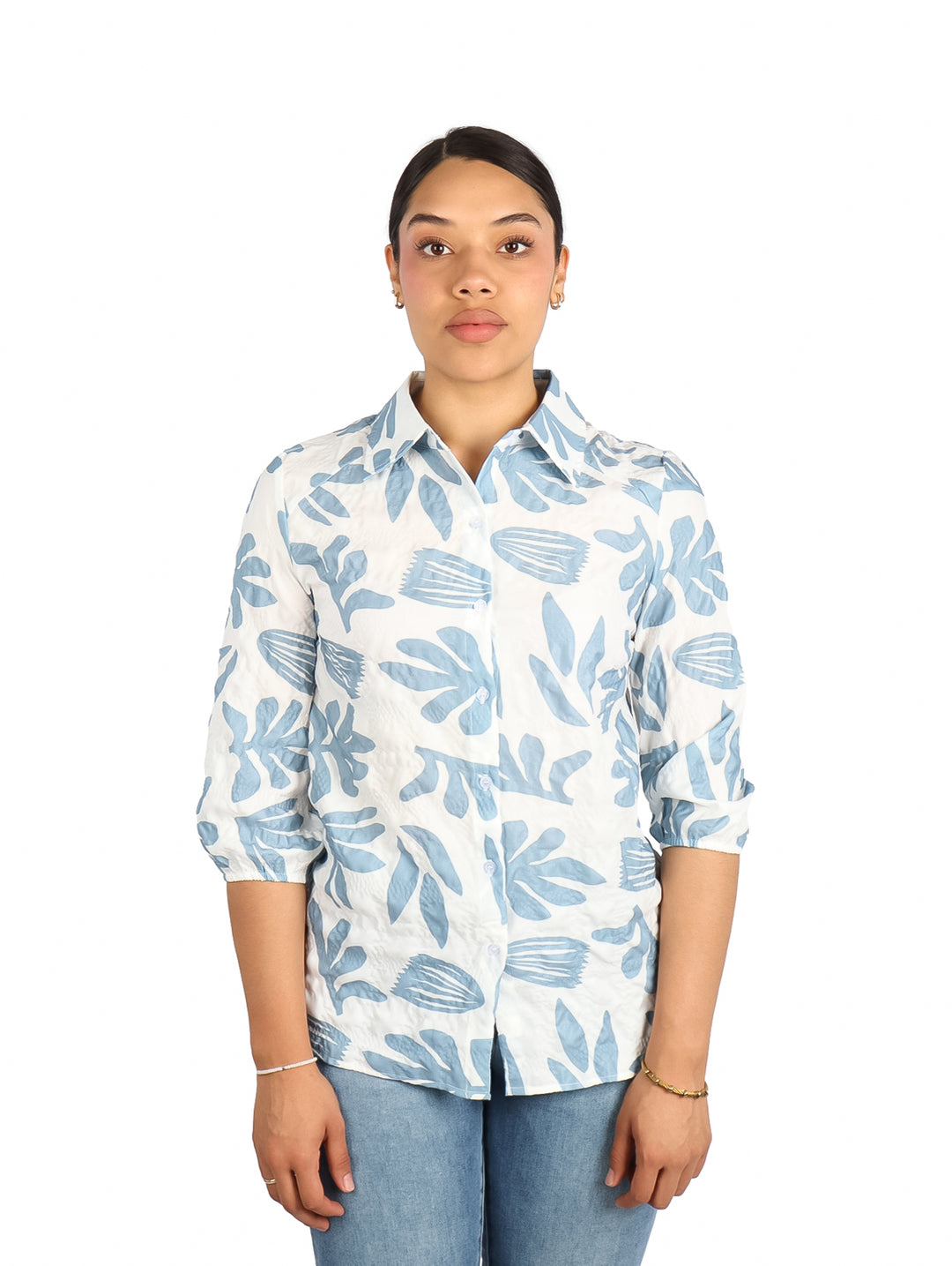 Mujer vistiendo una camisa blanca con estampado de hojas en color azul claro.