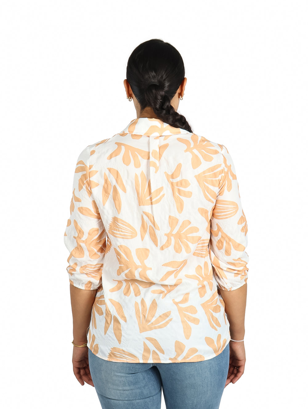 Mujer vistiendo camisa blanca de manga corta con estampado de hojas naranjas.